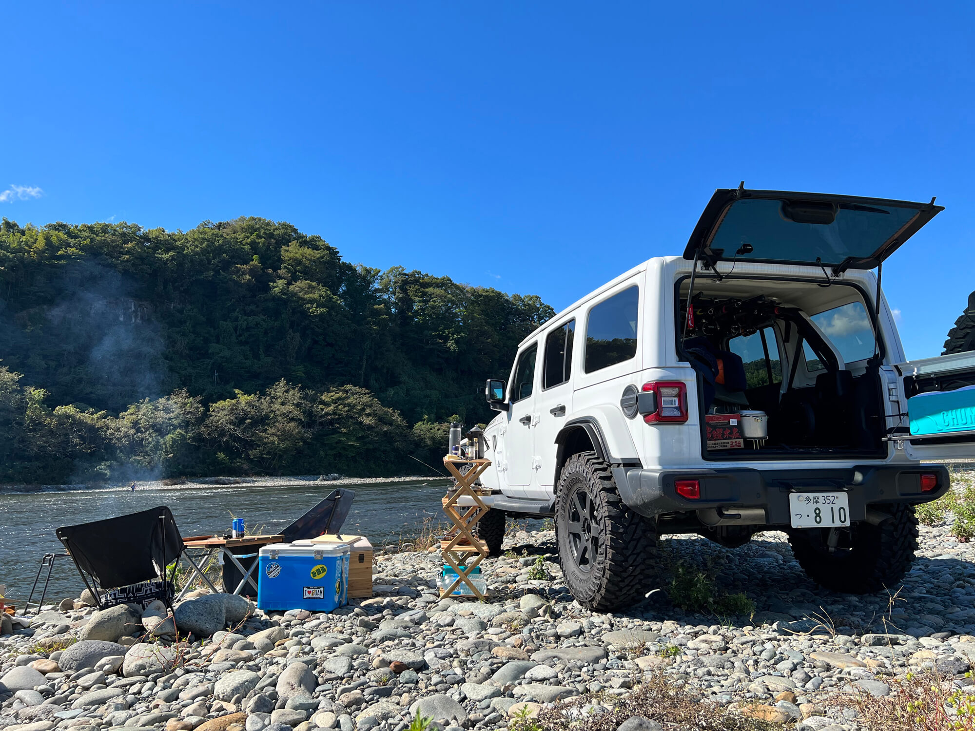 河川沿いに車を停めてキャンプをしている様子