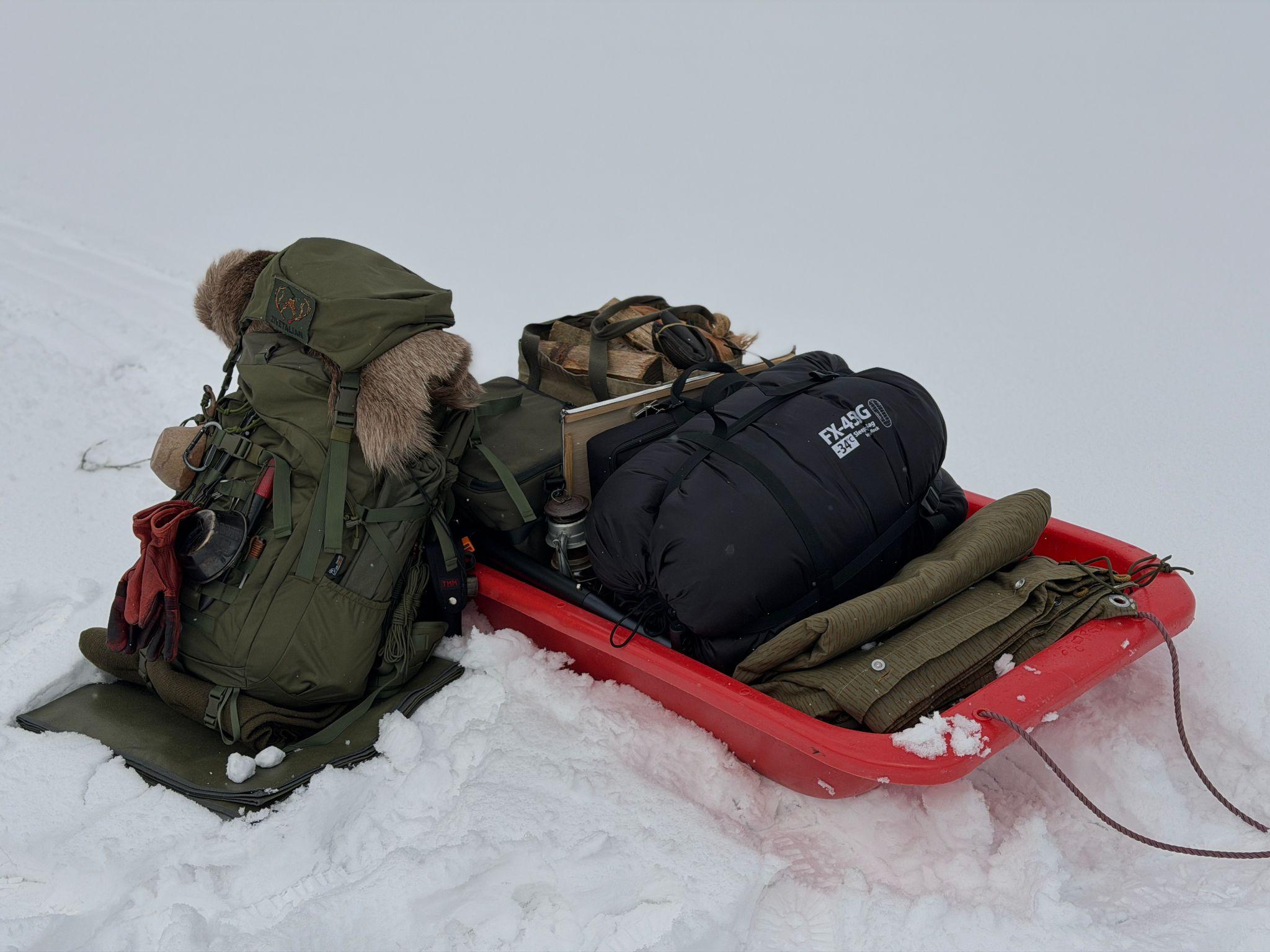寝袋とバックパックを載せた雪中キャンプの荷運び用ソリ